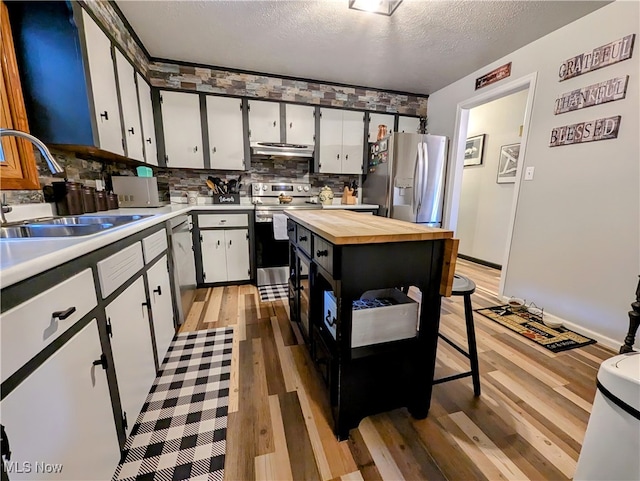 kitchen with light hardwood / wood-style flooring, appliances with stainless steel finishes, sink, and white cabinets