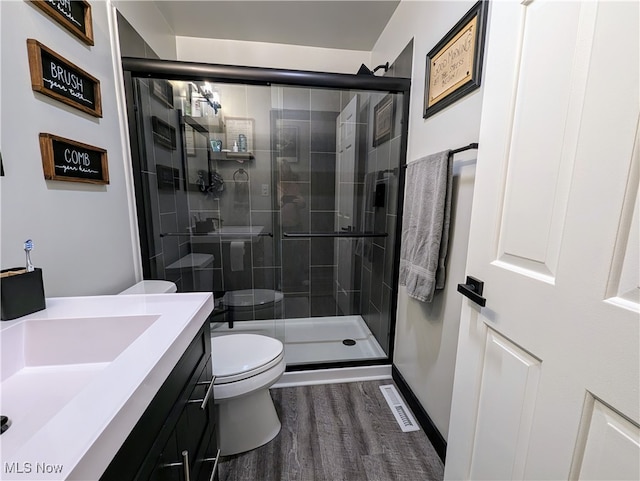 bathroom with vanity, hardwood / wood-style floors, toilet, and a shower with door