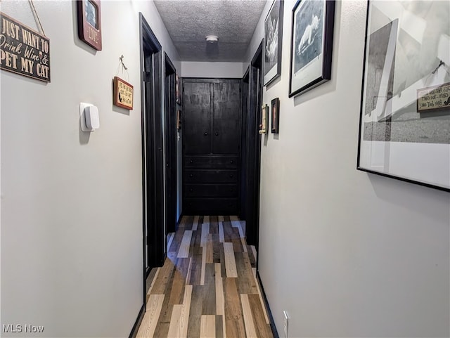 hallway featuring a textured ceiling and dark hardwood / wood-style floors