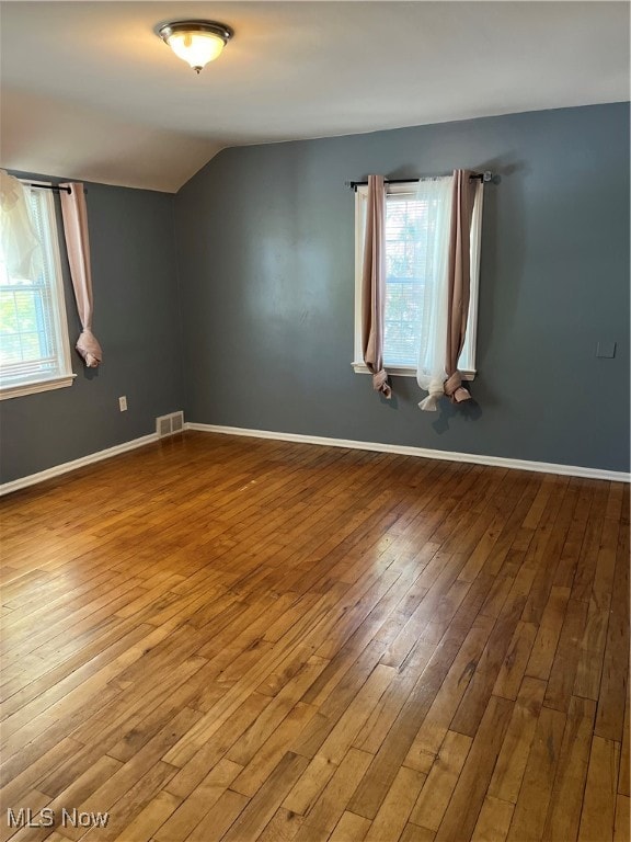 empty room featuring lofted ceiling and hardwood / wood-style flooring