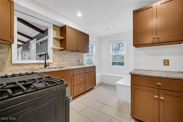 kitchen with backsplash, vaulted ceiling with beams, black gas range oven, and sink