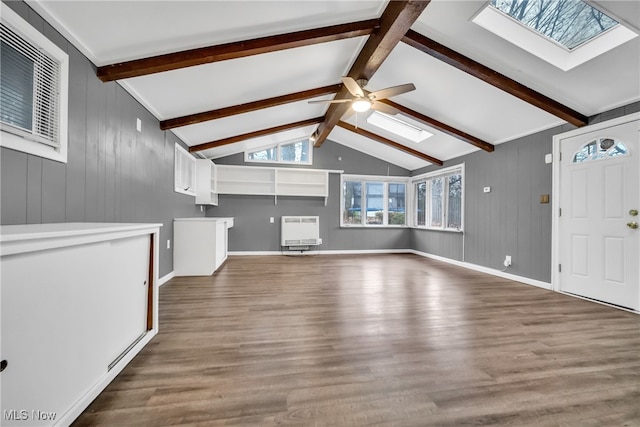 unfurnished living room with hardwood / wood-style floors, heating unit, lofted ceiling with skylight, and ceiling fan