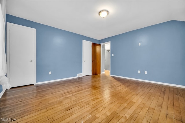 unfurnished room featuring hardwood / wood-style floors and lofted ceiling