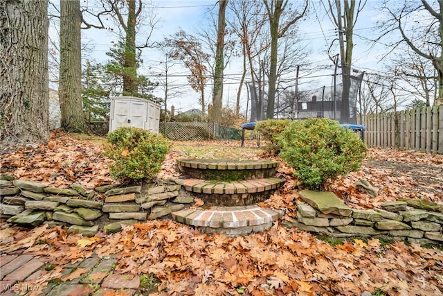 view of yard with a trampoline and a shed