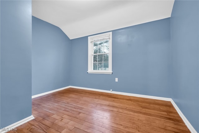 spare room with vaulted ceiling and hardwood / wood-style flooring