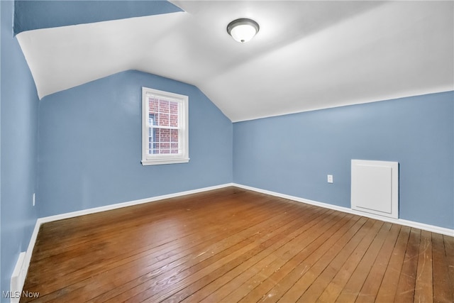 additional living space with hardwood / wood-style floors and lofted ceiling