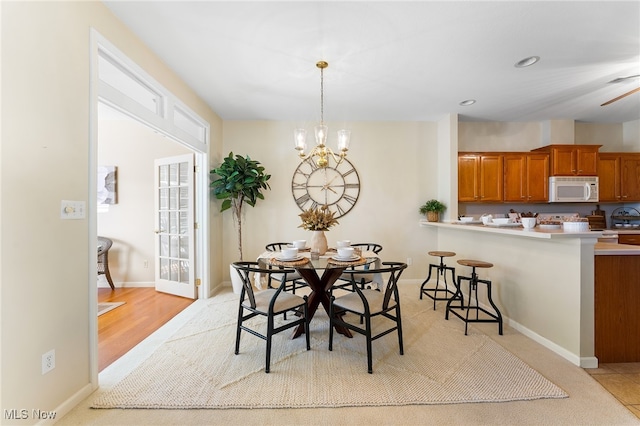 dining area featuring light wood-type flooring and ceiling fan with notable chandelier