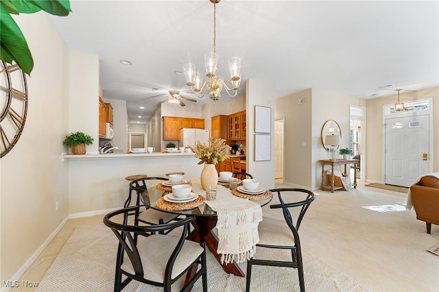 dining area featuring light colored carpet and ceiling fan with notable chandelier