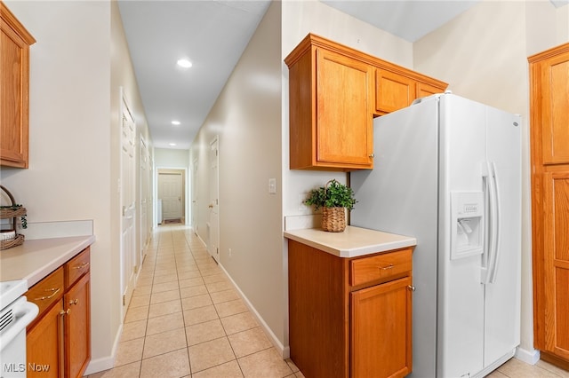 kitchen featuring white fridge with ice dispenser, stove, and light tile patterned floors