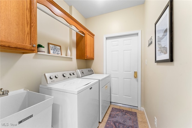 laundry room featuring sink, washer and dryer, light tile patterned floors, and cabinets