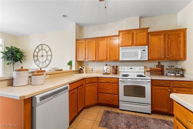 kitchen with white appliances, light tile patterned floors, sink, and kitchen peninsula