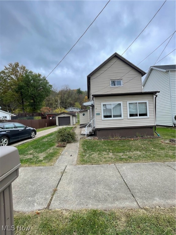 view of side of home with an outdoor structure, a yard, and a garage