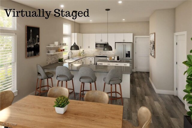 kitchen featuring a peninsula, appliances with stainless steel finishes, a sink, and a wealth of natural light