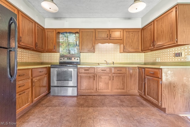 kitchen with stainless steel electric range, a textured ceiling, black refrigerator, and sink