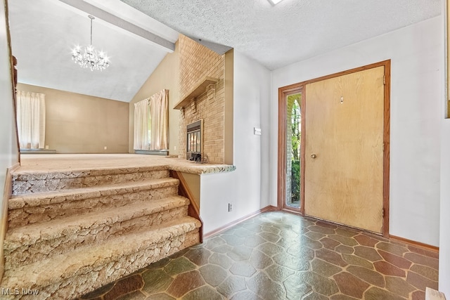 entrance foyer featuring vaulted ceiling with beams, a notable chandelier, a textured ceiling, and a fireplace