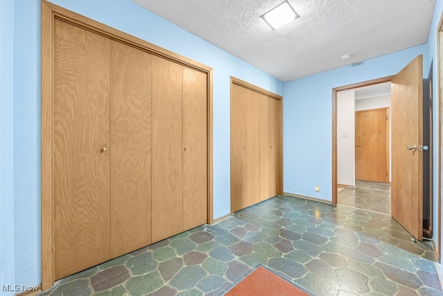 unfurnished bedroom featuring a textured ceiling and multiple closets