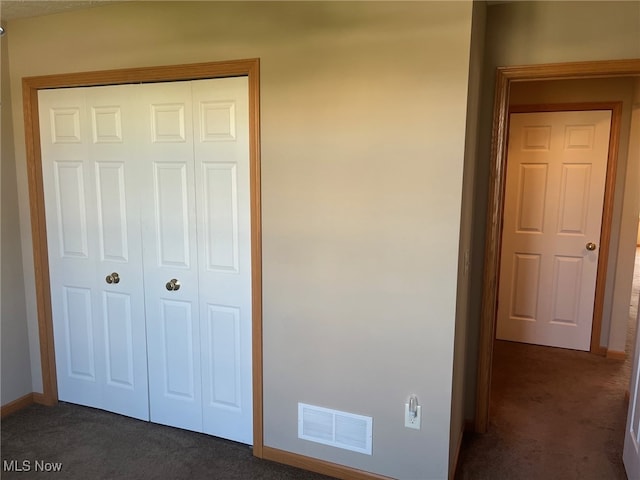 unfurnished bedroom with dark carpet and a closet