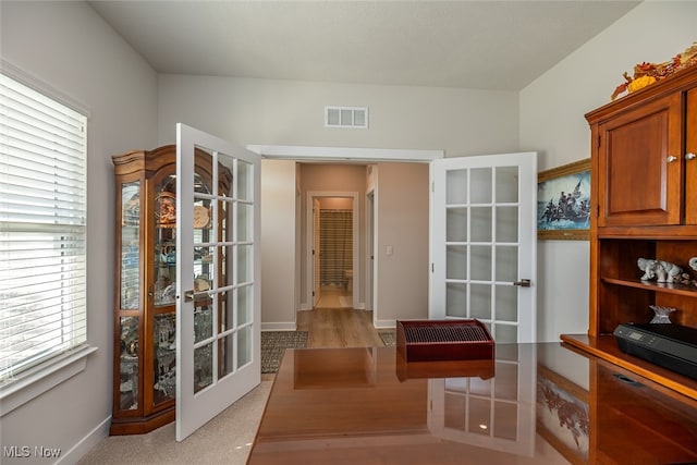 interior space with french doors and light colored carpet