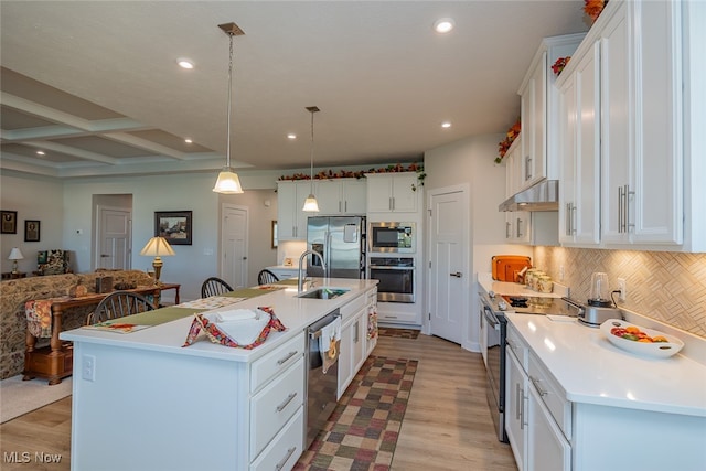 kitchen featuring white cabinets, hanging light fixtures, appliances with stainless steel finishes, a kitchen island with sink, and light hardwood / wood-style flooring