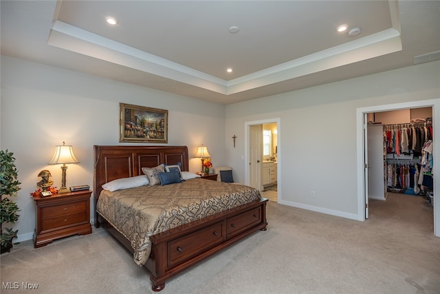 carpeted bedroom featuring a closet, a spacious closet, ensuite bath, and a raised ceiling