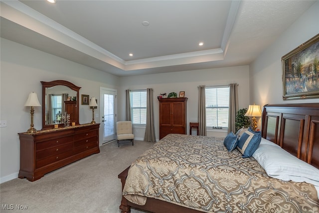 bedroom with light carpet, a tray ceiling, and multiple windows