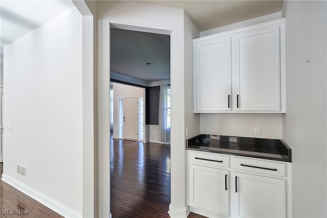 bar with white cabinets and dark hardwood / wood-style floors