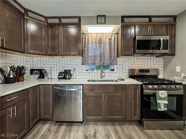 kitchen with light hardwood / wood-style floors, dark brown cabinetry, stainless steel appliances, and sink