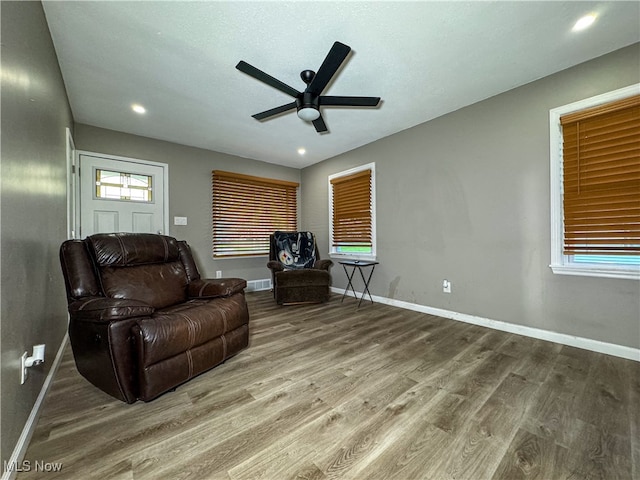 sitting room with wood-type flooring, a healthy amount of sunlight, and ceiling fan