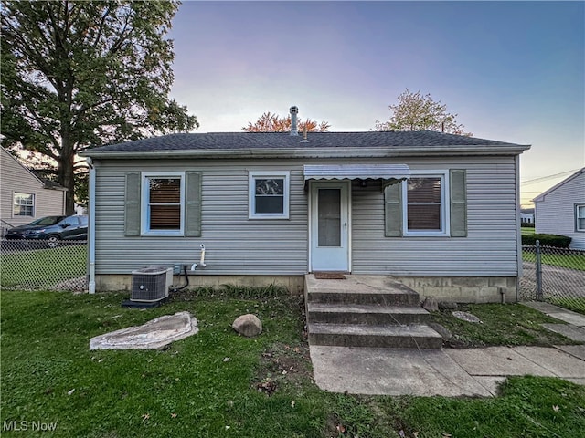 bungalow with a lawn and central AC unit