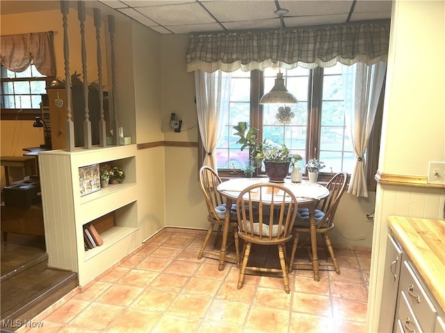 tiled dining room featuring a paneled ceiling