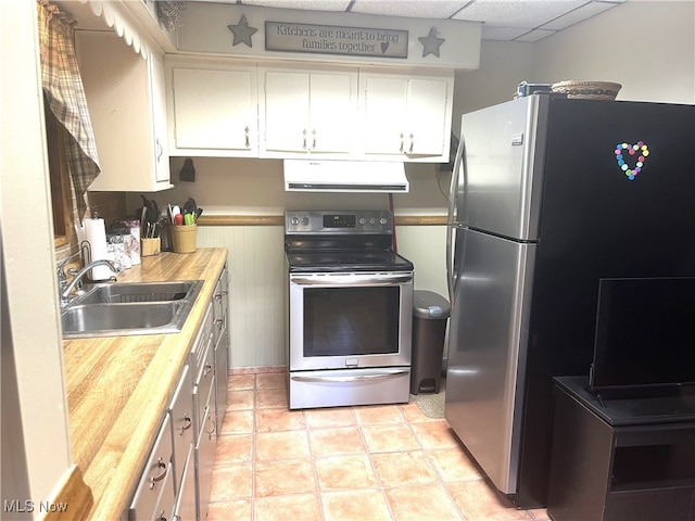 kitchen featuring sink, wood counters, range hood, white cabinets, and appliances with stainless steel finishes