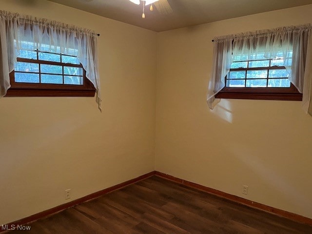 empty room featuring dark hardwood / wood-style flooring, ceiling fan, and a healthy amount of sunlight