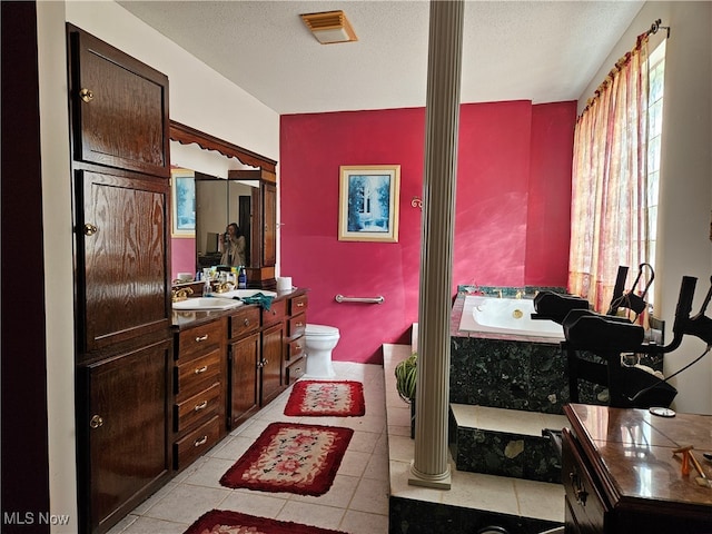 bathroom featuring a tub, a textured ceiling, toilet, vanity, and tile patterned flooring