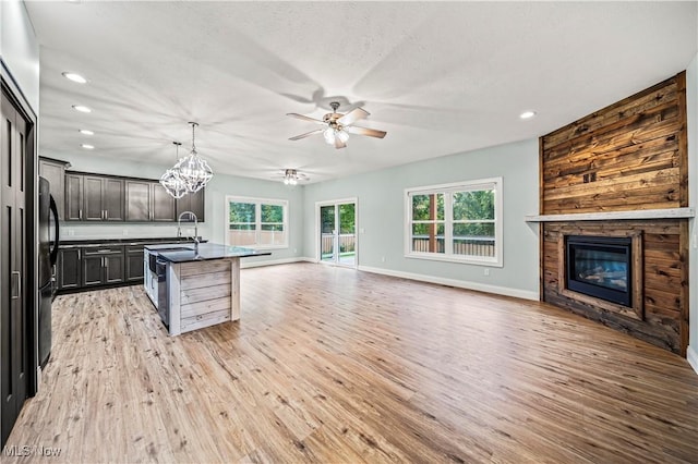 kitchen with pendant lighting, light hardwood / wood-style flooring, a fireplace, fridge, and an island with sink