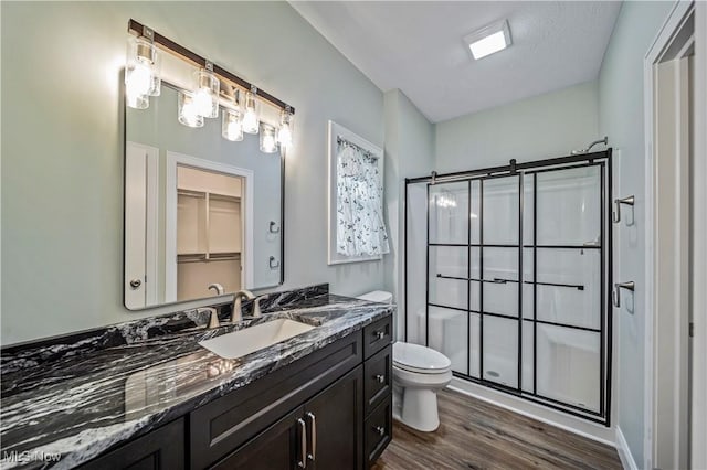 bathroom featuring vanity, a textured ceiling, hardwood / wood-style floors, toilet, and a shower with shower door