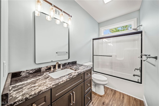 full bathroom featuring toilet, vanity, bath / shower combo with glass door, and hardwood / wood-style flooring