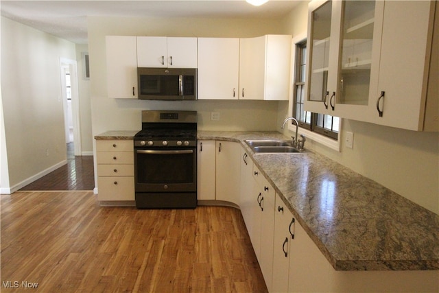 kitchen featuring light stone countertops, appliances with stainless steel finishes, sink, light hardwood / wood-style flooring, and white cabinets