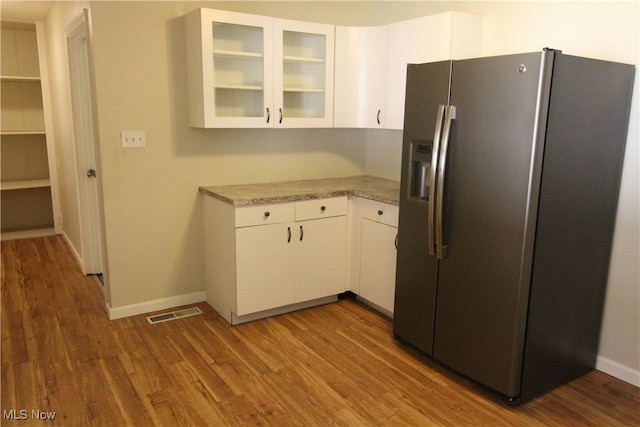 kitchen featuring white cabinetry, light stone countertops, stainless steel refrigerator with ice dispenser, and hardwood / wood-style flooring