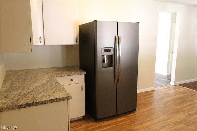 kitchen with stainless steel fridge with ice dispenser, white cabinets, and light wood-type flooring