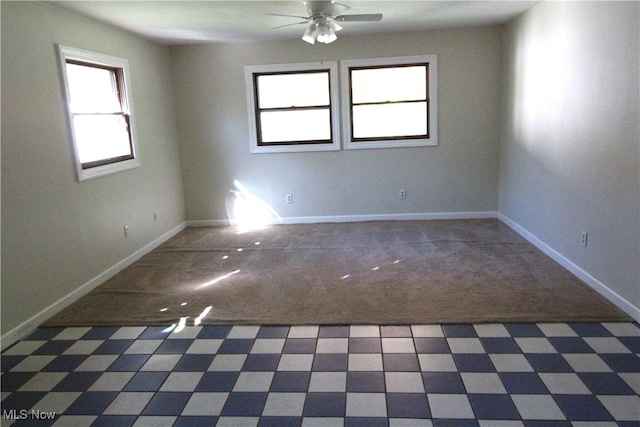 carpeted empty room with ceiling fan and plenty of natural light