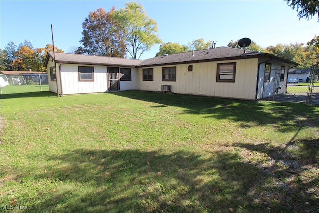 back of house featuring central air condition unit and a lawn