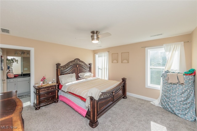 carpeted bedroom featuring ensuite bath, sink, and ceiling fan