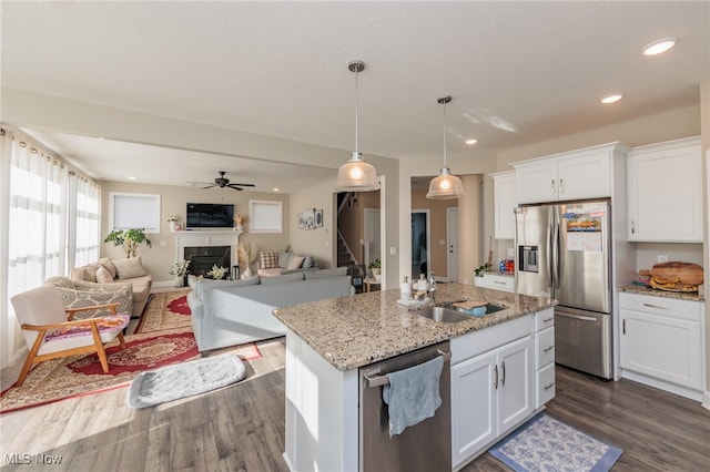 kitchen with white cabinetry, light stone countertops, appliances with stainless steel finishes, and a kitchen island with sink