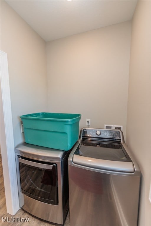 laundry room featuring washing machine and dryer and light hardwood / wood-style flooring