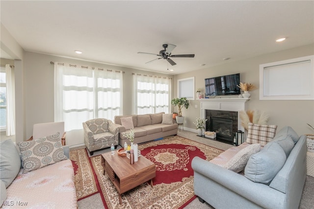 living room with carpet, a premium fireplace, and ceiling fan