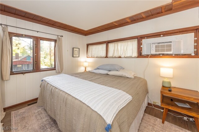 bedroom with light hardwood / wood-style floors, cooling unit, and wooden walls