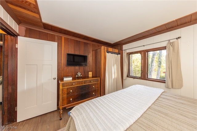 bedroom featuring light hardwood / wood-style floors and wood walls