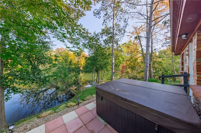 view of patio with a water view and a hot tub