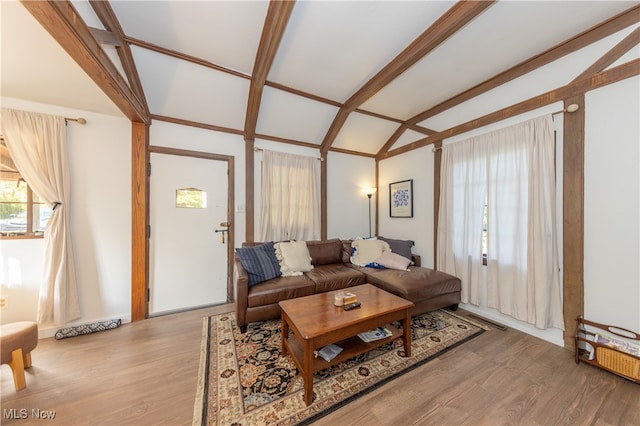 living room featuring wood-type flooring and vaulted ceiling with beams