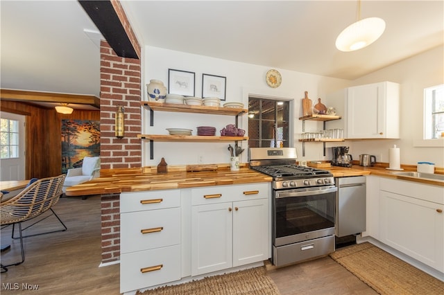 kitchen with butcher block counters, hanging light fixtures, white cabinetry, stainless steel appliances, and hardwood / wood-style flooring